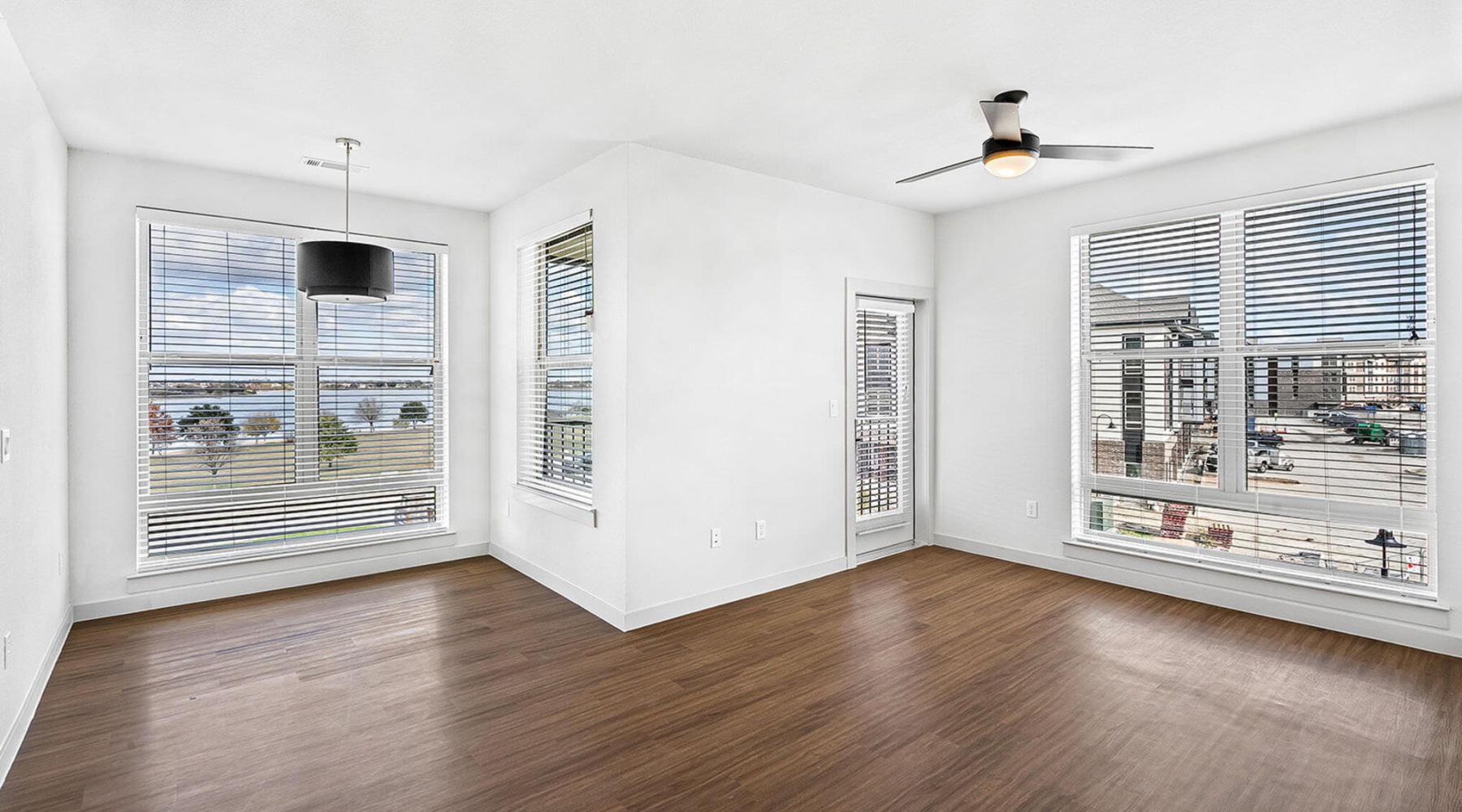 a room with a wood floor and a wood floor with a television and a window with blinds